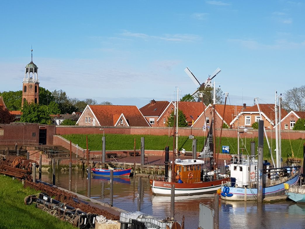 Hafen mit Kirchturm und Mühle in Ditzum